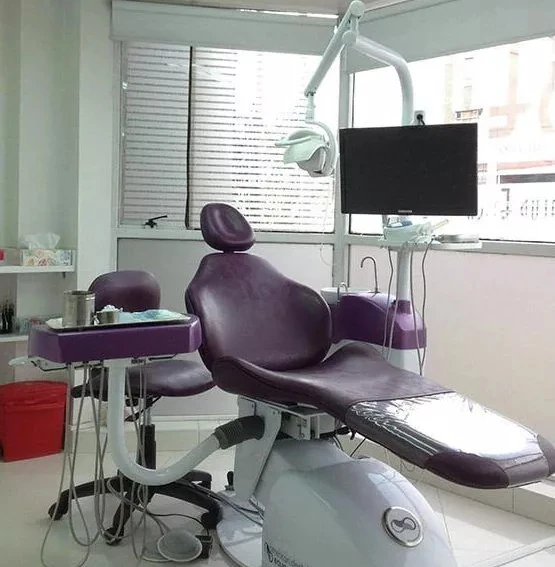 Consulta dental en La Clínica Dental Clínica Country, sillón odontológico morado y equipo moderno en consultorio luminoso.